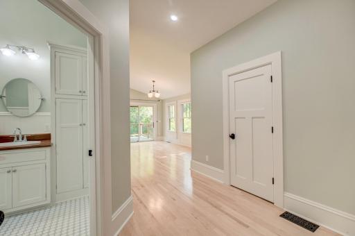 This hallway is in the primary suite with en suite bathroom to the left and walk-in closet on the right.
