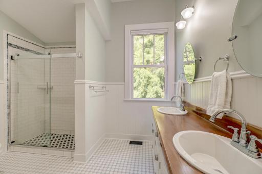 Spacious tiled shower and double sinks with a rich cherry-stained vanity top.
