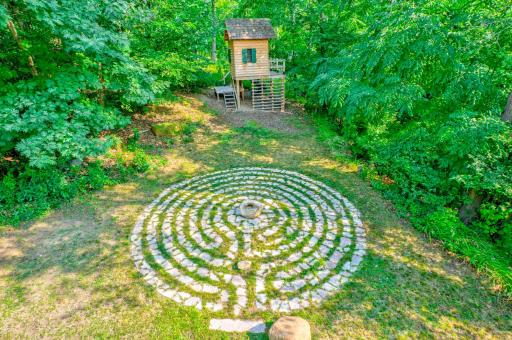 With the addition of the tree house and labyrinth, the back yard is both meditative and playful! The woodsy property is very private in all directions.