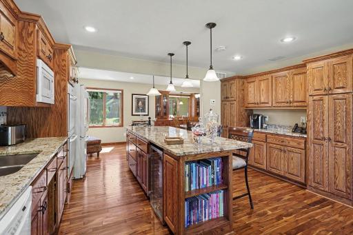 Kitchen with custom cabinets, granite countertops, and an island with built-in wine fridge. Sound system controlled by remote or kitchen volume switch.