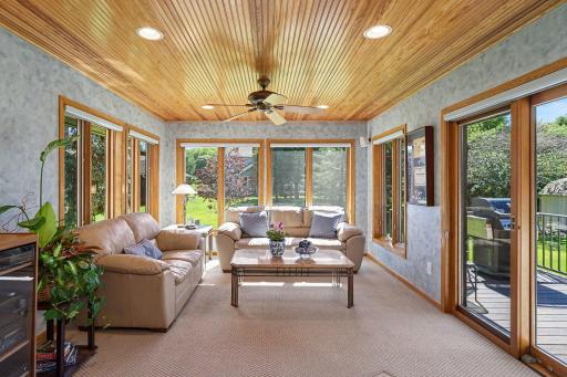 Four-season porch with wood ceilings, heated floors, large windows, and sound system.