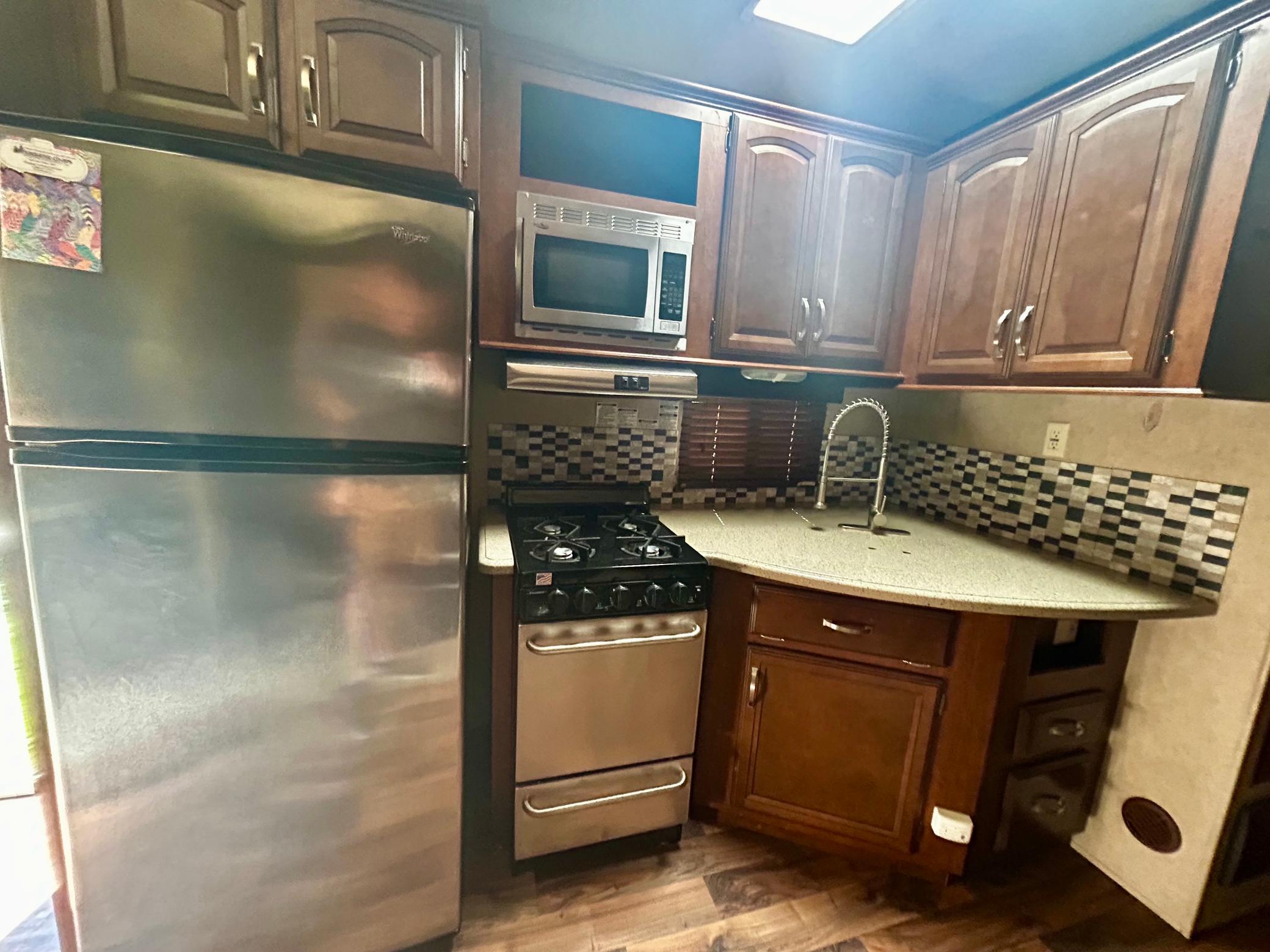 Camper One - Main kitchen area with a gas stove, a full-size refrigerator, a microwave, and plenty of storage
