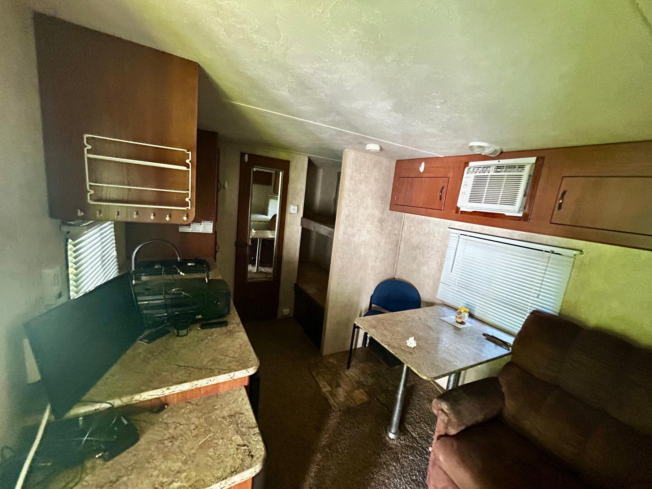 Camper Two - Main living area, loaded up, cozy and functional, with AC, a full-sized bed, a bathroom with a shower, and two single beds