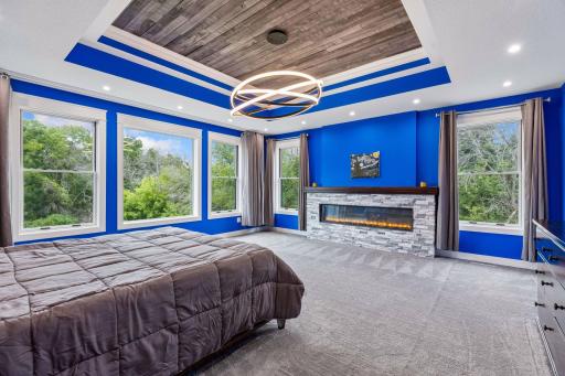 The Primary Suite features Double doors, a 6 ft electric fireplace, Layered lighting – 5000k recessed lights that surround the room, and Chandelier lighting – 3000k.