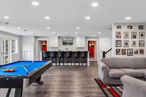 Recreation space including a pool table, wine wall and kitchenette with double doors leading to the back patio. 