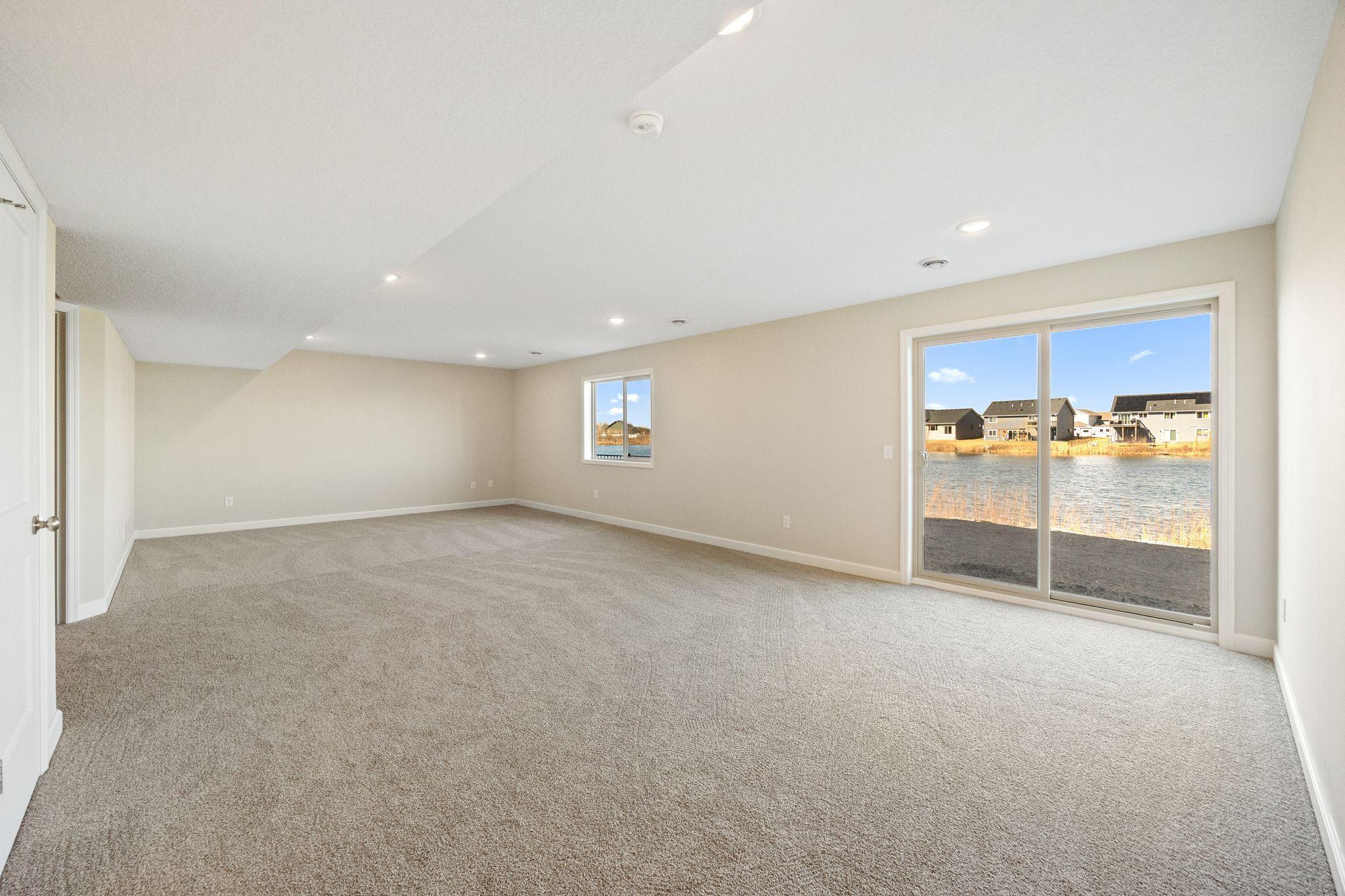 Finished lower level rec room - home for sale is not a walk-out. There will be 2 windows in this space and no sliding glass door - this photo is not this exact home, but one of the same floorplan