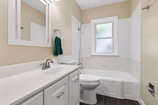 The main floor full bath has a white tub with tile surround