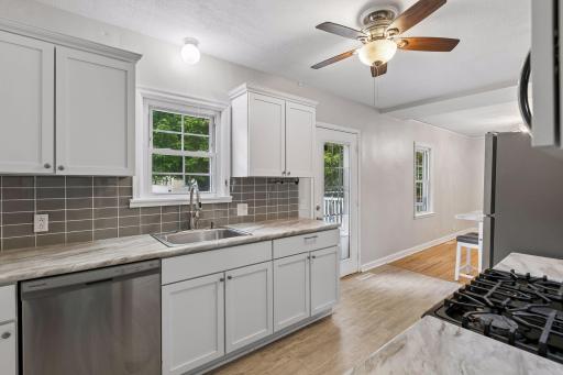 The updated kitchen has a tile backsplash with a west facing window
