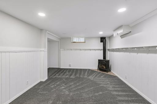 The lower level family room has newer carpeting in 2024 and a cozy gas stove