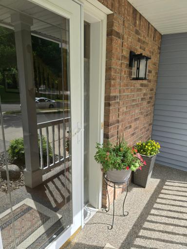 Full glass storm door with washed stone porch and sidewalk.