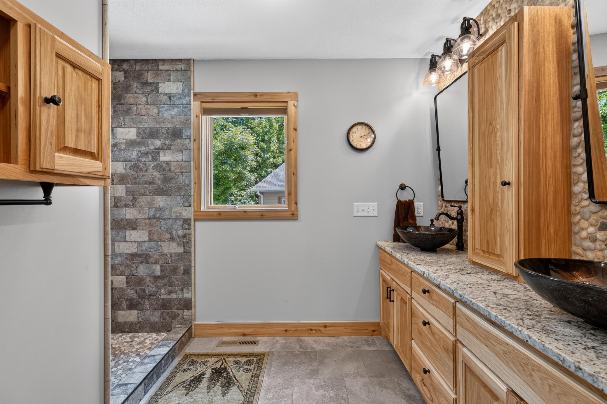Primary bathroom with double sinks, tile shower and custom cabinets.