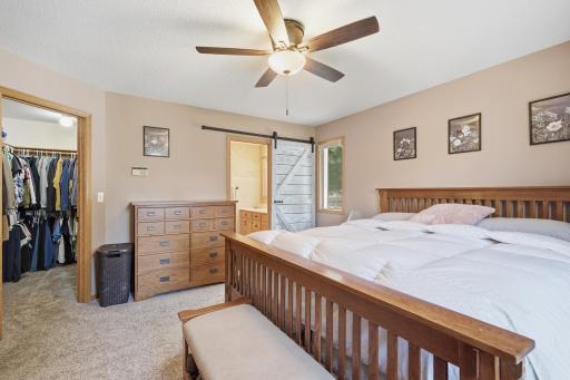 The primary suite has a quaint barndoor leading the the bathroom and a large walk-in closet.