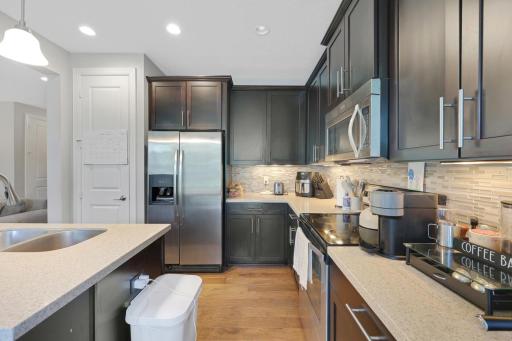 [*pardon the garbage can and cords, but] check out the granite counters, and tile backsplash. The below-cabinet lights are hardwired to a switch (and a great touch!)