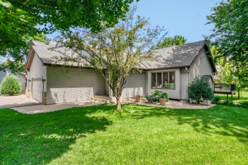 A welcoming covered entry is framed by mature trees, beautifully maintained landscaping, and decorative rock beds, creating exceptional curb appeal from the moment you arrive.