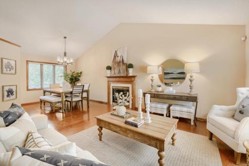 The heart of the home is this bright and inviting open-concept main living area, where soaring vaulted ceilings create a spacious yet welcoming atmosphere. The comfortable living room is anchored by a cozy gas fireplace w/oak mantle for MN winters