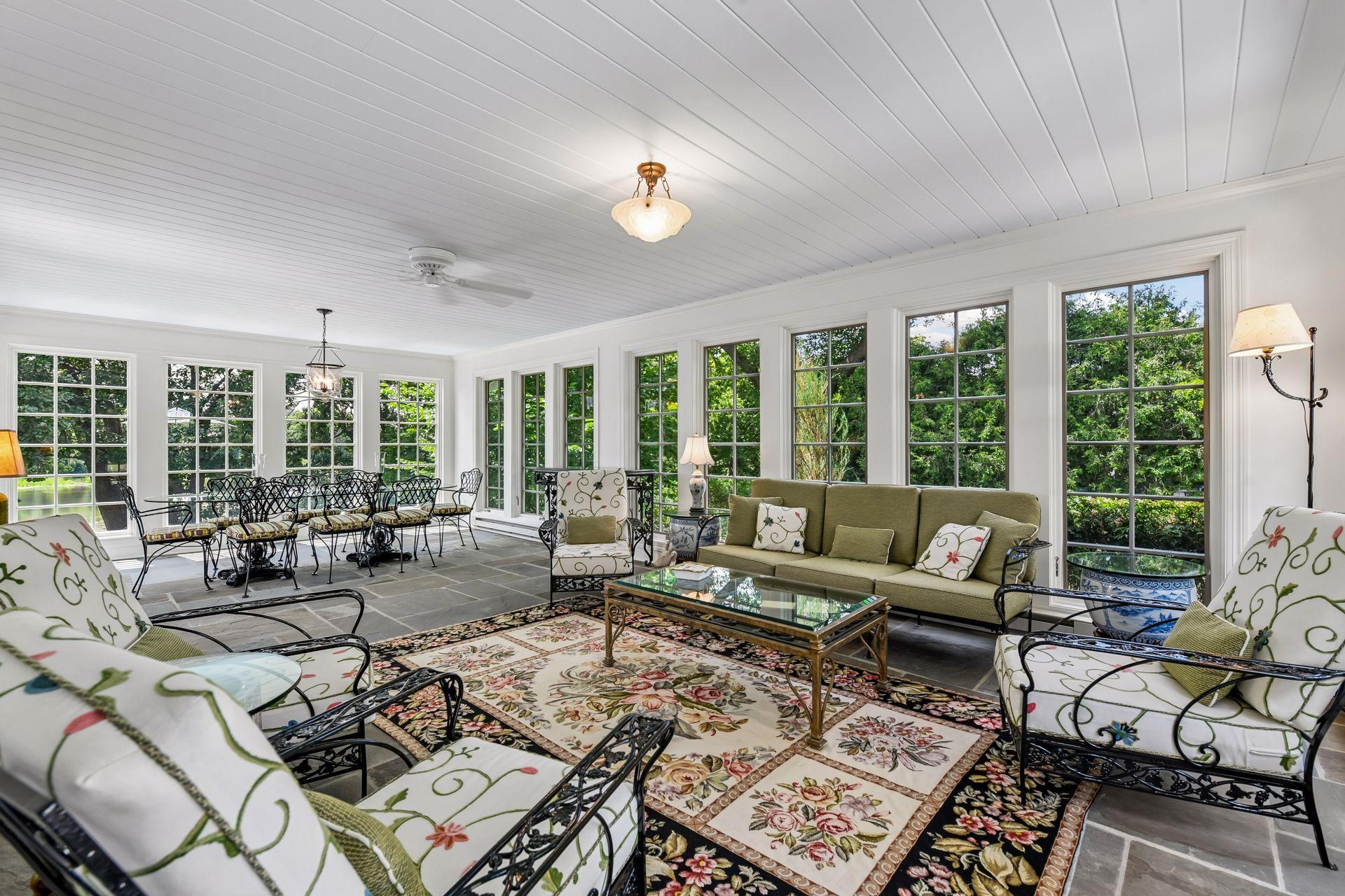 Newly remodeled sunroom with glass windows, blue slate stone flooring and access to deck.