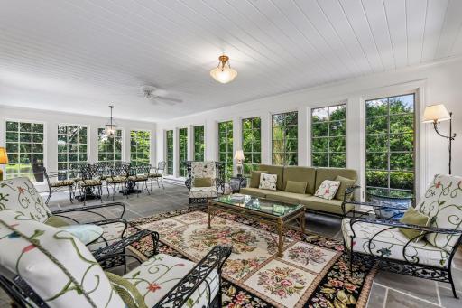 Newly remodeled sunroom with glass windows, blue slate stone flooring and access to deck.