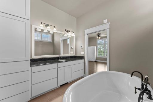 Primary Bathroom featuring heated floors, a single-basin granite countertop vanity, plus a pocket door and maple cabinetry offering additional storage and convenience, with premium Kohler plumbing fixtures.
