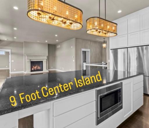 A 9-foot center island features a built-in microwave, concealed waste storage, and abundant cabinetry, creating a refined focal point with generous workspace for everyday living and entertaining.