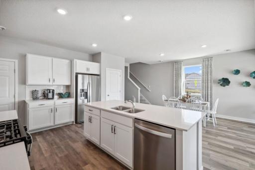 The kitchen island provides additional seating, storage, and ample space to prep meals or set up a buffet for entertaining. Photo of model home , colors and finishes will vary.