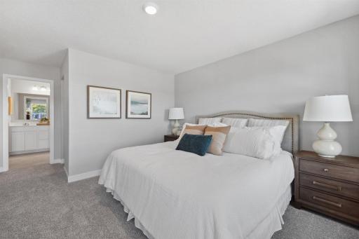 Here is an alternate view of the primary bedroom looking into the en-suite bathroom and just to the right is one of the two walk-in closets. Photo of model home, colors and finishes will vary.