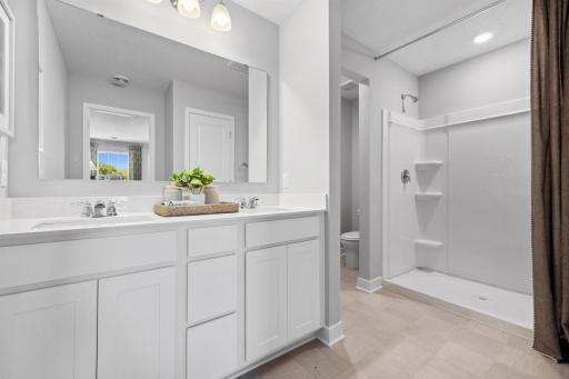 The dual sinks are a great addition to the en-suite bathroom and the large walk-in shower has corner shelves for all of your shower essentials. Photo of model home, colors and finishes will vary.