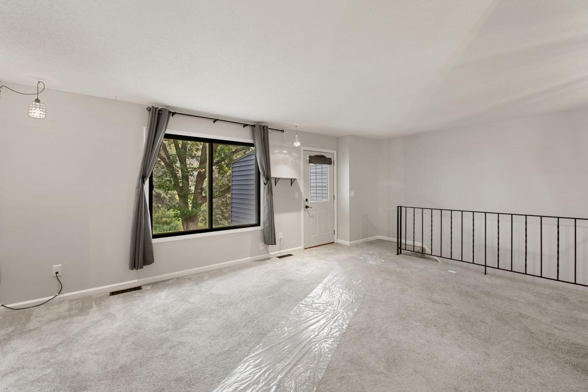 Large living room looks over park like yard with a pond in the distance.