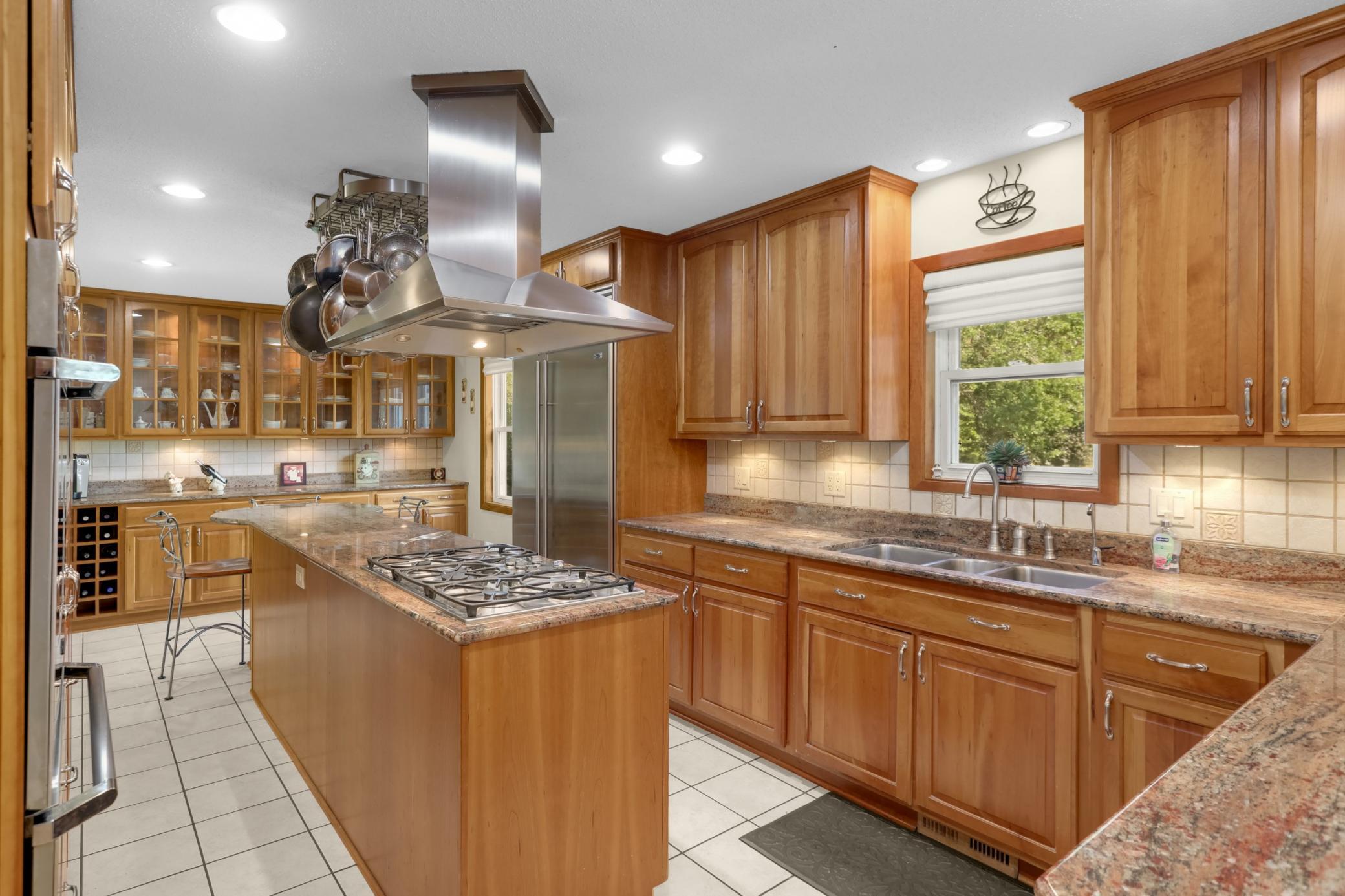 Gourmet Kitchen w/ large center island, granite counters, custom cherry cabinetry, stainless steel appliances and hood.
