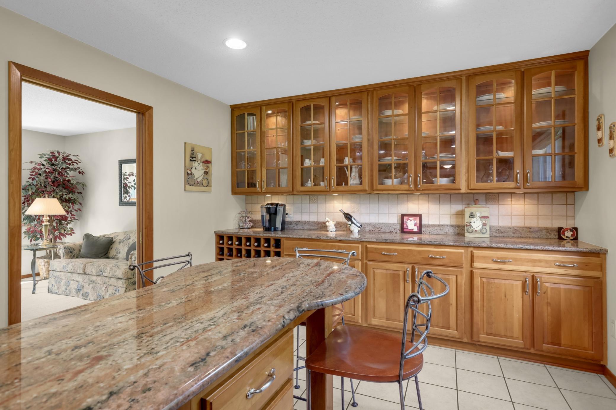 Custom built dry bar w/ glass-front cherry cabinetry, granite countertop and wine storage.