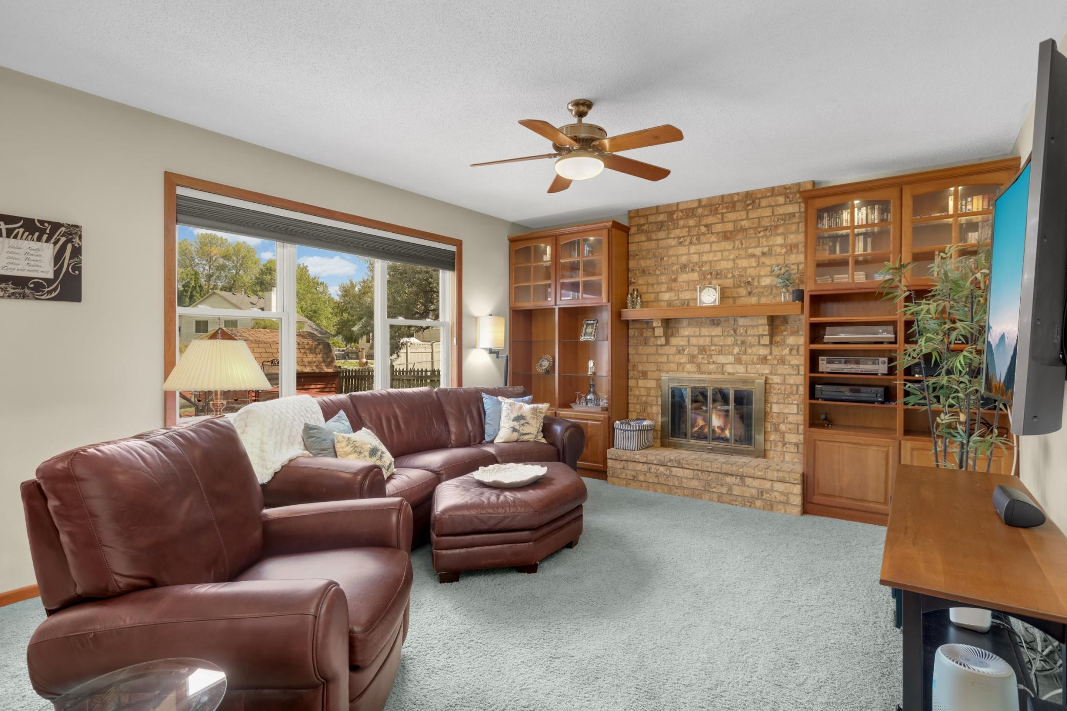 Inviting family room w/ brick wood burning fireplace, custom cherry built-ins, and a large picture window overlooking the backyard.