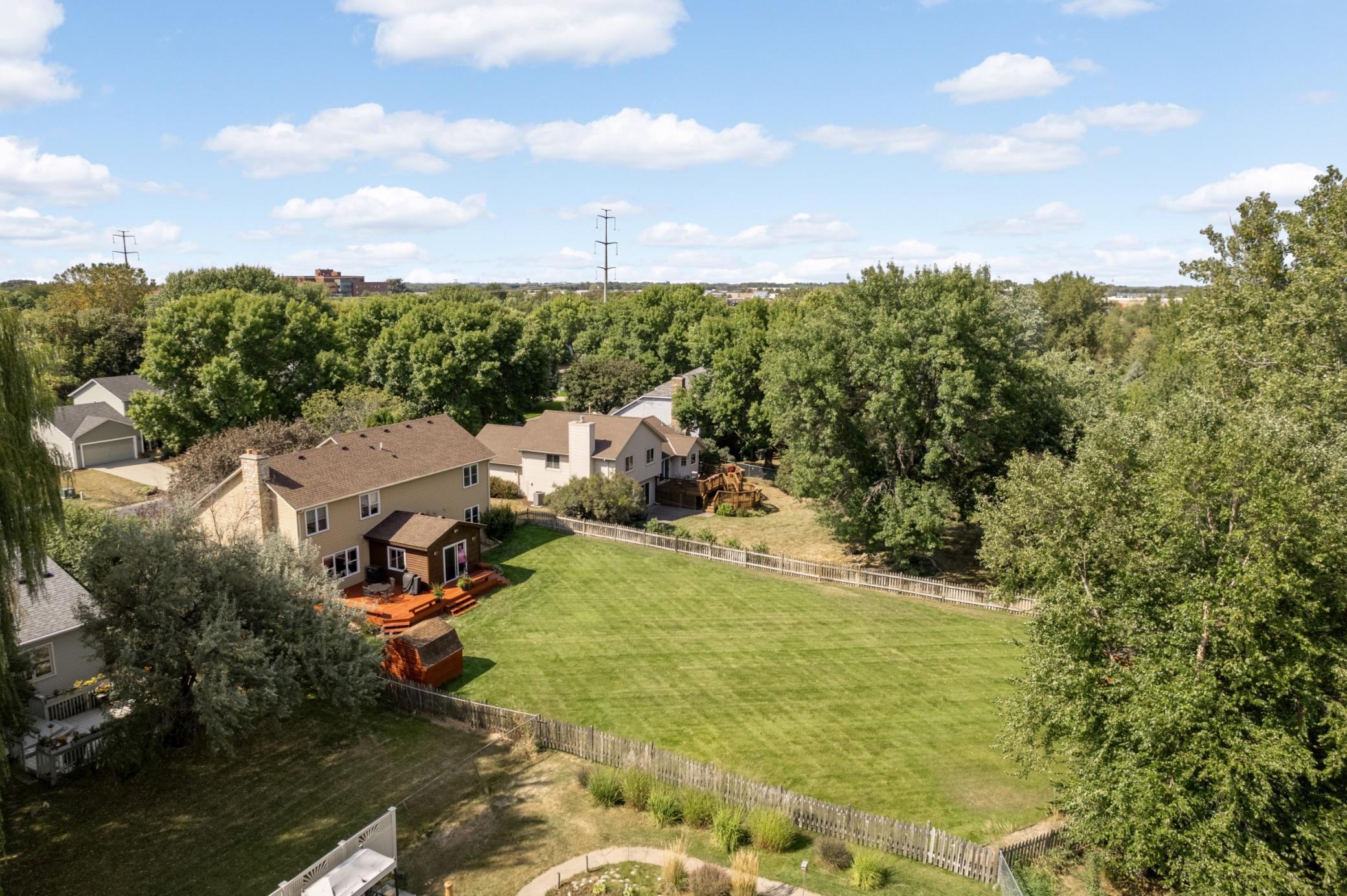 Expansive fenced backyard with a spacious deck, and two storage sheds.