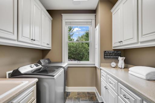 Spacious main-level laundry room with custom cabinetry, utility sink and abundant storage.
