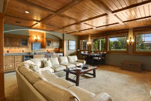 Spectacular lower level recreation room showcasing a hand crafted wood ceiling, custom wet bar and spacious gathering area.