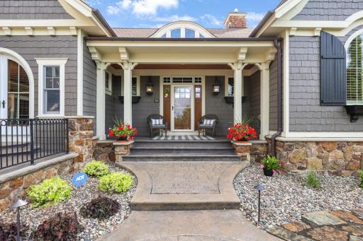 Grand covered porch showcasing timeless architecture, rich stone accents, and an inviting first impression.