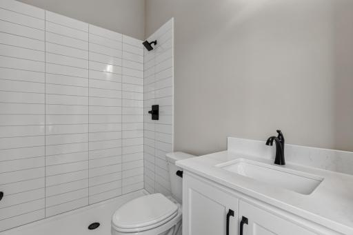 Private 3/4 bathroom features enameled vanity cabinet w/ quartz countertop and luxury vinyl tile flooring. Shower features a ceramic tile surround
