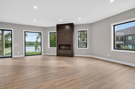 Great Room features corner gas fireplace with decorative tile surround. Floor to ceiling windows provide stunning views of Hanrehan Lake