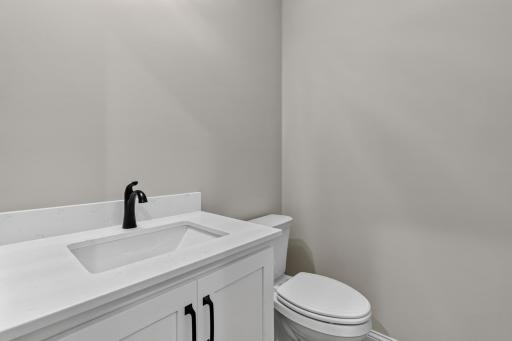 1/2 bathroom features enameled vanity cabinet with quartz countertop