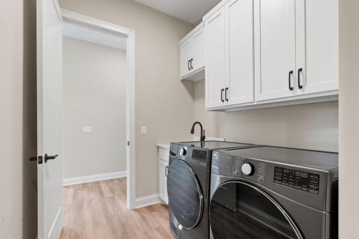 Laundry Room features enameled cabinetry with quartz countertop and composite utility sink