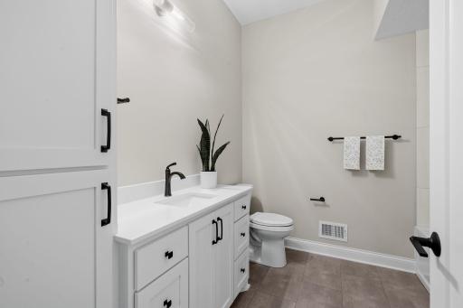 Private Full Bathroom features Enameled vanity cabinet w/ quartz countertop, linen cabinet and modern tile flooring.