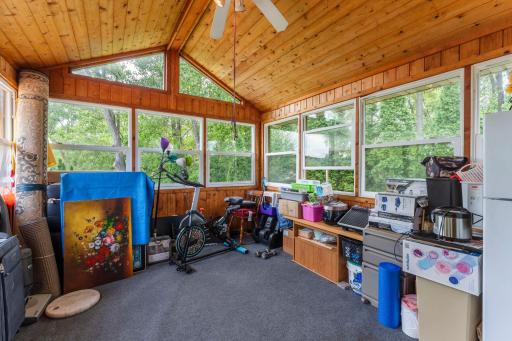 Vaulted sun room porch has windows on all 3 sides with ceiling fan above.