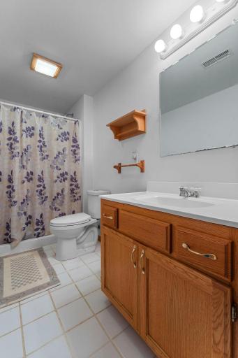 Lower level full hallway bathroom with wide vanity and tile floor.