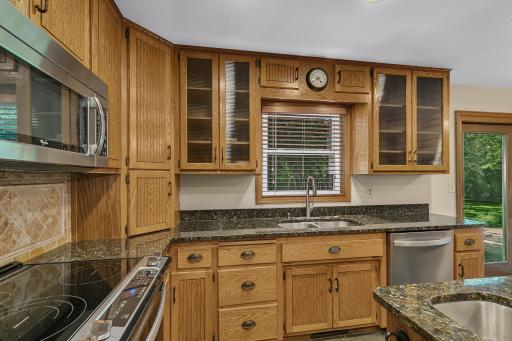 The kitchen features granite countertops, a tiled backsplash, and an abundance of cabinetry.