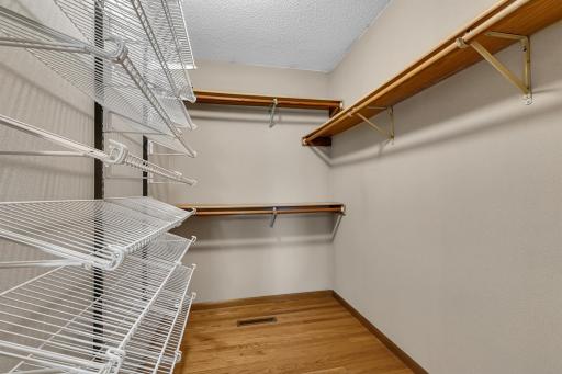 Walk-in closet with multiple shelves and clothes hanging rods.