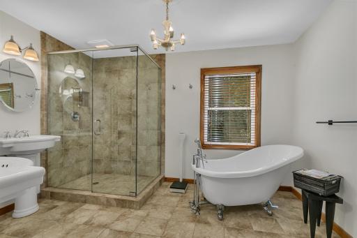 The private bath features a glass-enclosed walk-in shower with tiled surround, and a separate soaking tub.