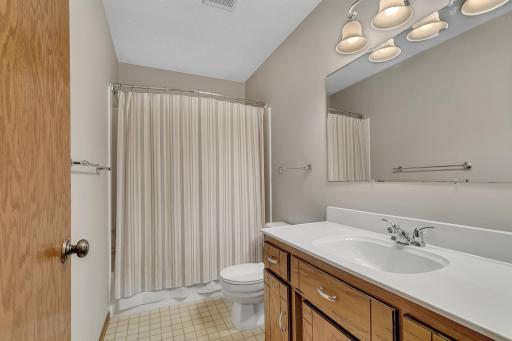 Upper level full bath with large vanity, shower/tub unit and tiled flooring.
