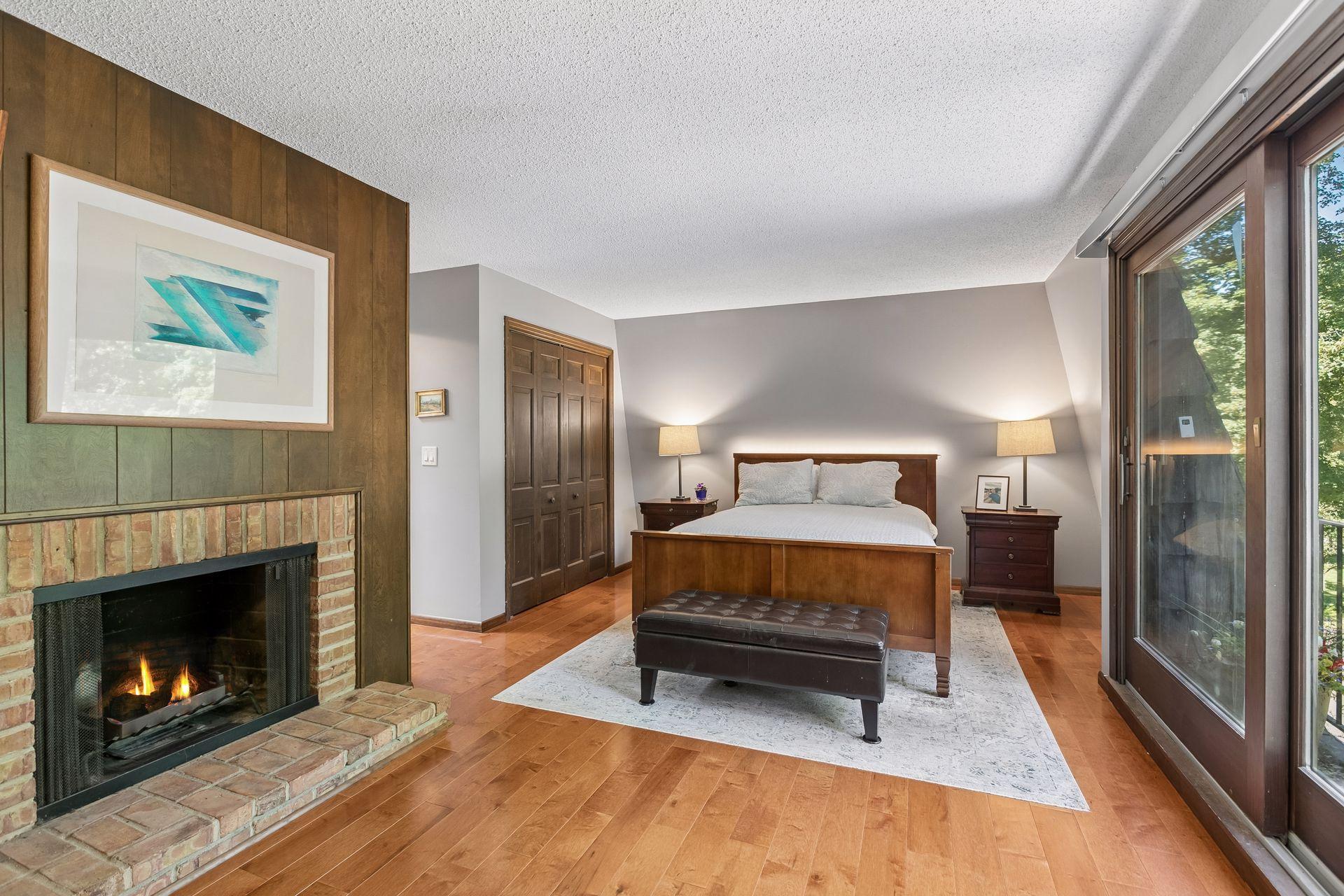 The upper level boasts three bedrooms, including this enormous primary suite with decorative fireplace (flames are photoshopped) and private bathroom.