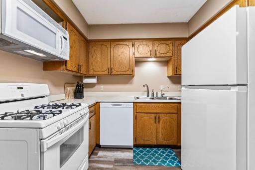 The kitchen has a gas oven and all-white appliances.