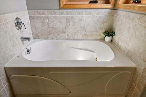 Jetted tub in primary with tile surround.