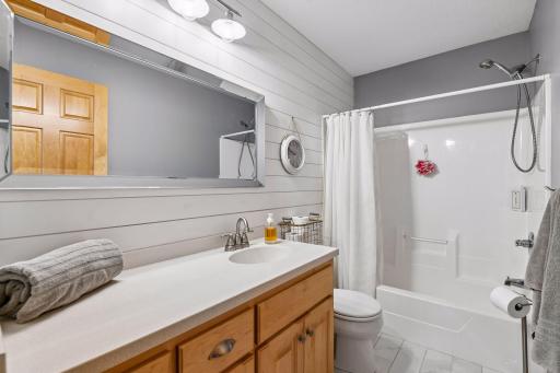 Upper level updated bath with tile floors, shiplap accent wall, new mirror, and new lighting.