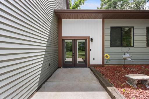 A wide sidewalk leads to an inviting covered entry with double glass doors